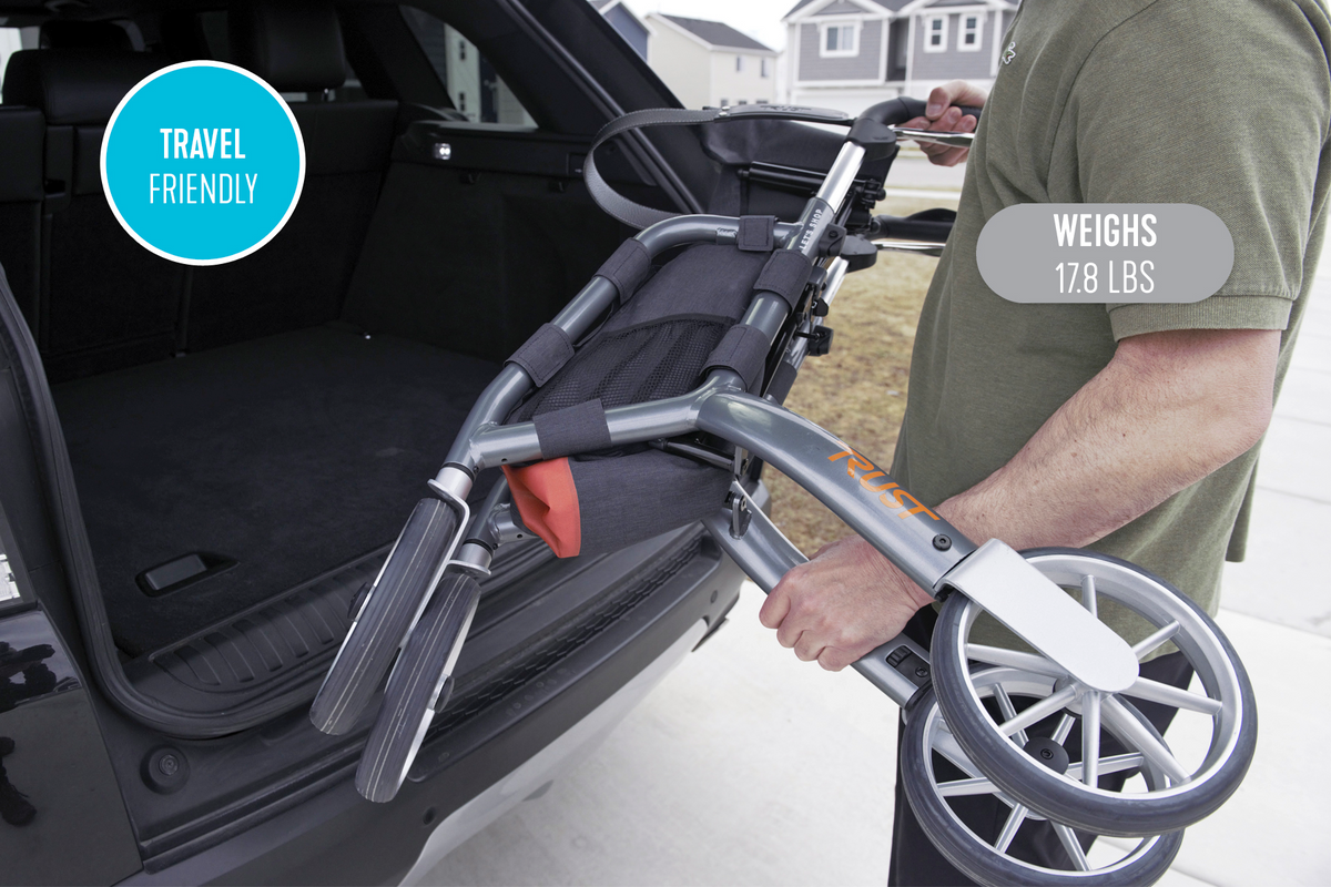 Folded Let's Shop Rollator being lifted into an SUV trunk by a person, shown collapsed for compact travel storage