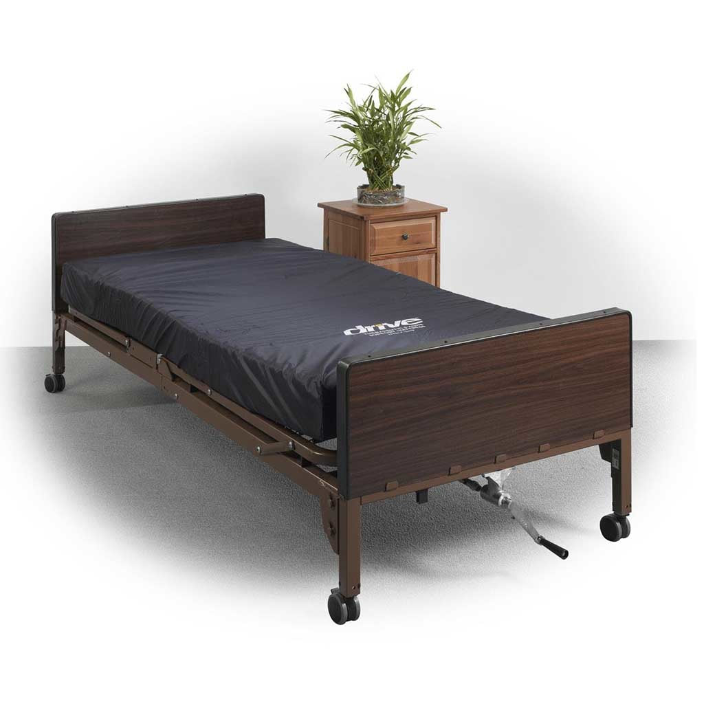 Full electric hospital bed with dark wood-grain finish, casters, and black mattress, shown beside a wooden nightstand with a