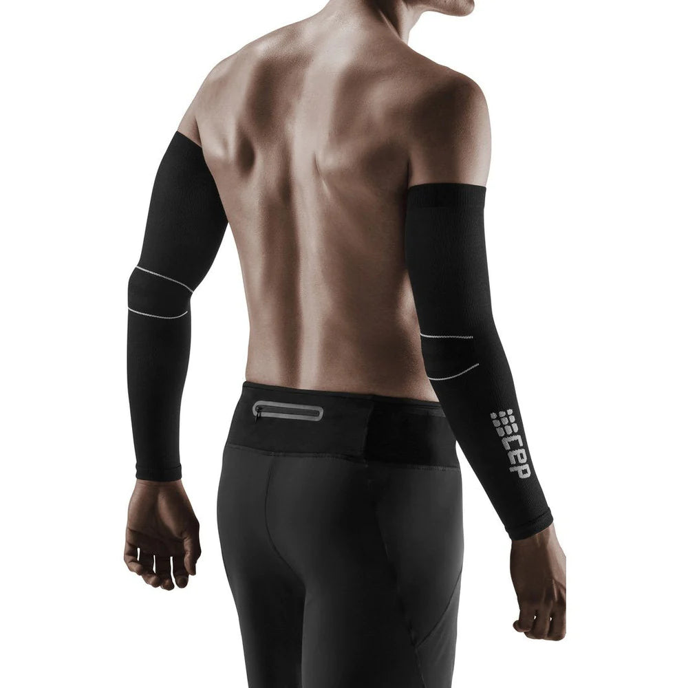 Compression arm sleeves in black with reflective detailing, shown on a man's bare arms from behind