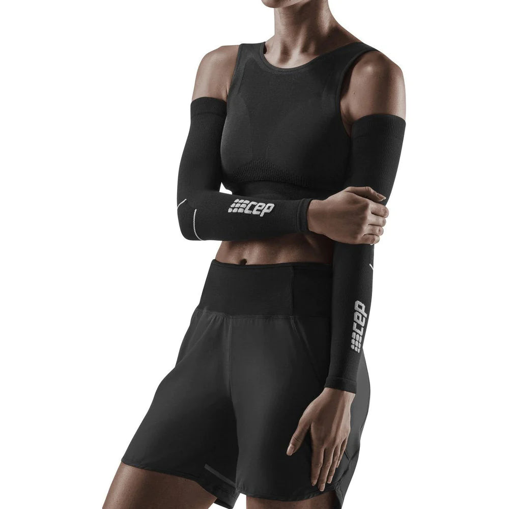 Compression arm sleeves in black worn by a female model, featuring CEP branding and reflective accents