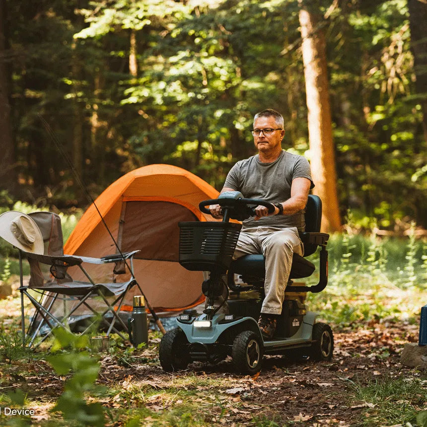 Baja Bandit 4-wheel mobility scooter ridden by a man at a wooded campsite with an orange tent in the background