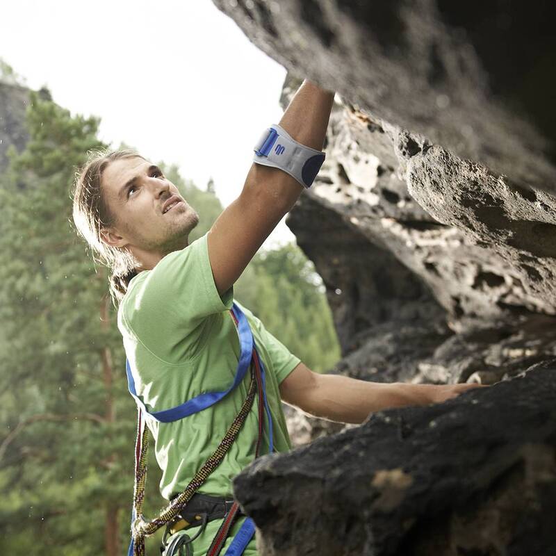 Elbow strap with blue closure worn on a man's forearm while rock climbing outdoors