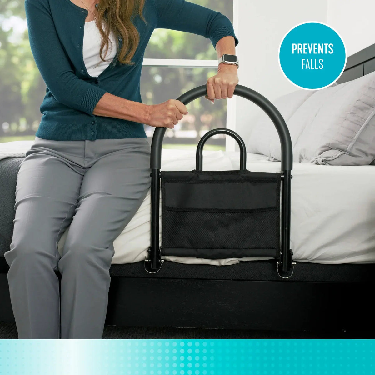 Bed rail with arched black metal frame and storage pocket, used by a woman gripping the handle while seated on the edge of a
