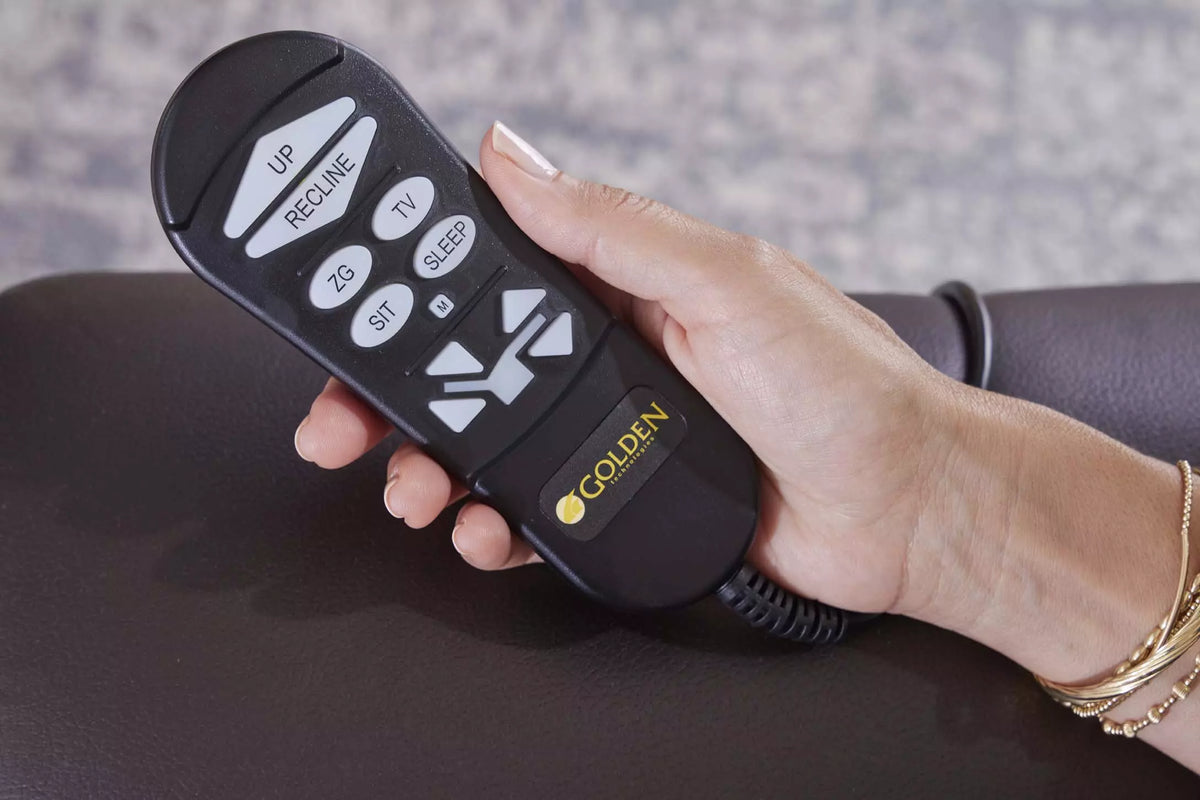 Lift chair remote control with recline, sit, ZG, TV, and sleep buttons held in a woman's hand against a brown leather armrest