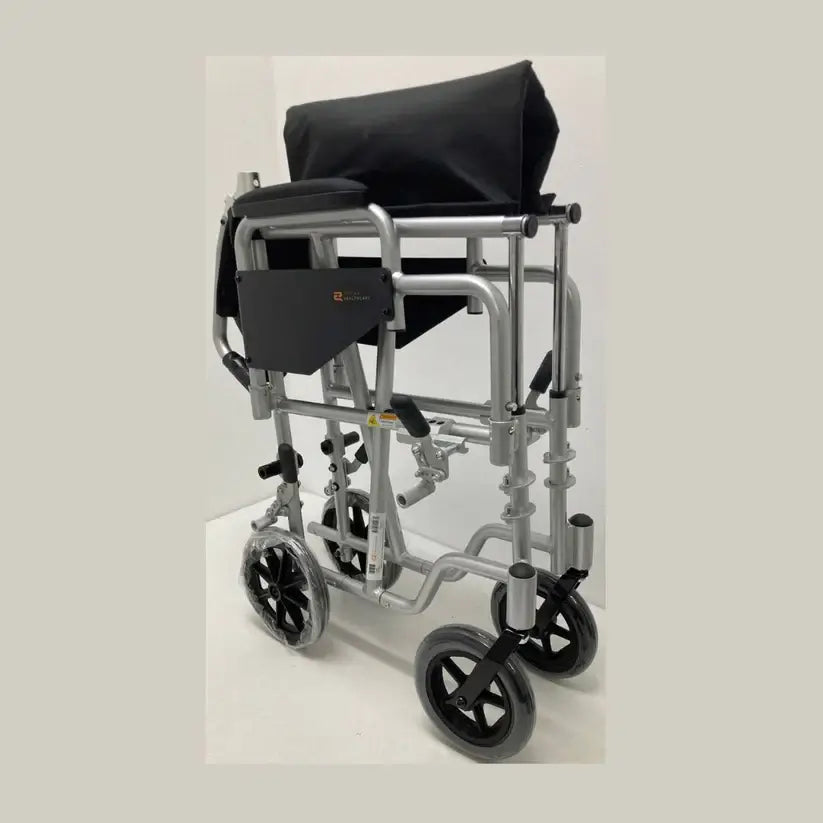 Transport wheelchair with silver frame, black upholstery, swing-away footrests, and small rear wheels, shown from the side