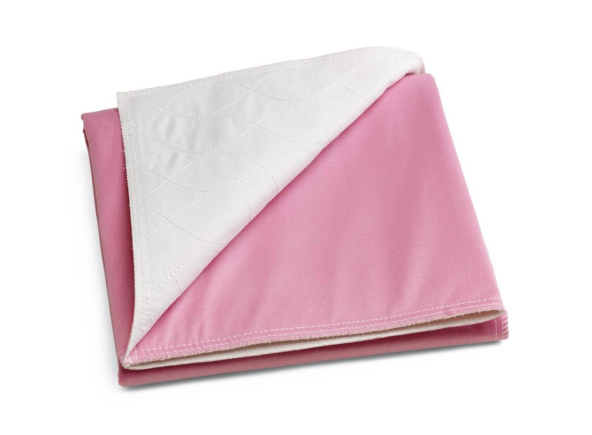 Reusable underpad folded to show pink outer fabric and white quilted inner surface