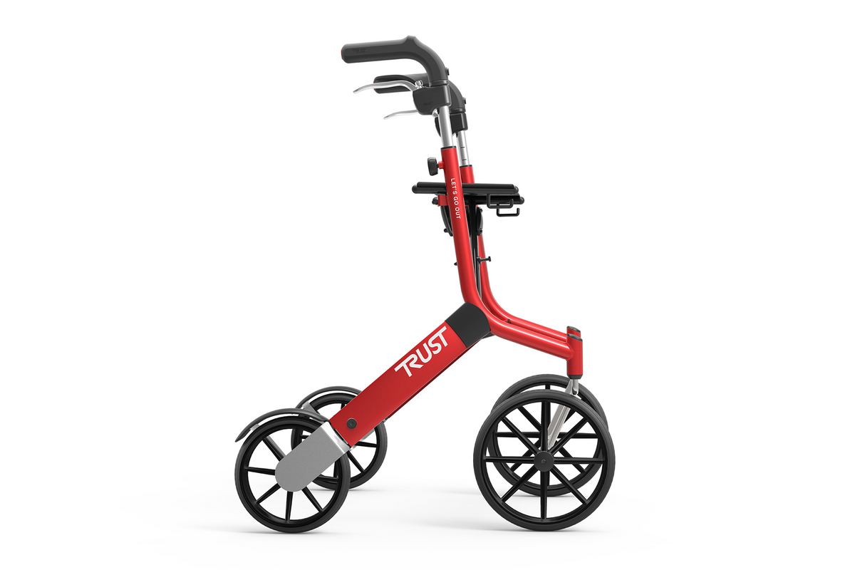 Rollator walker in red with large spoke wheels, loop hand brakes, and padded seat, shown from the side on white background