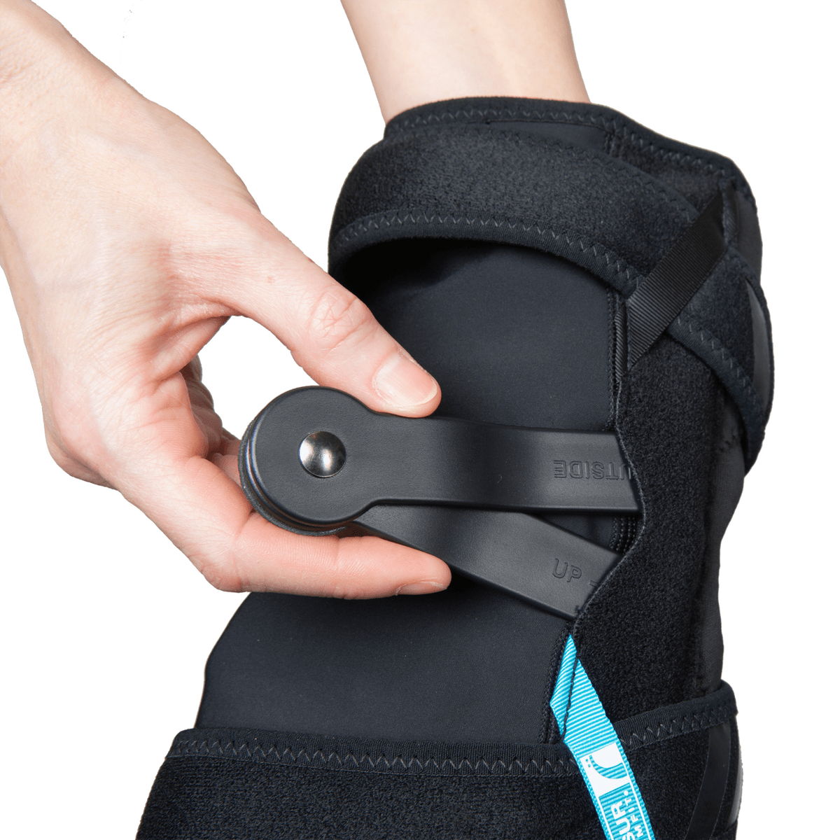 Knee brace with black neoprene wrap worn on leg, hand adjusting a circular dial hinge mechanism on the outer side