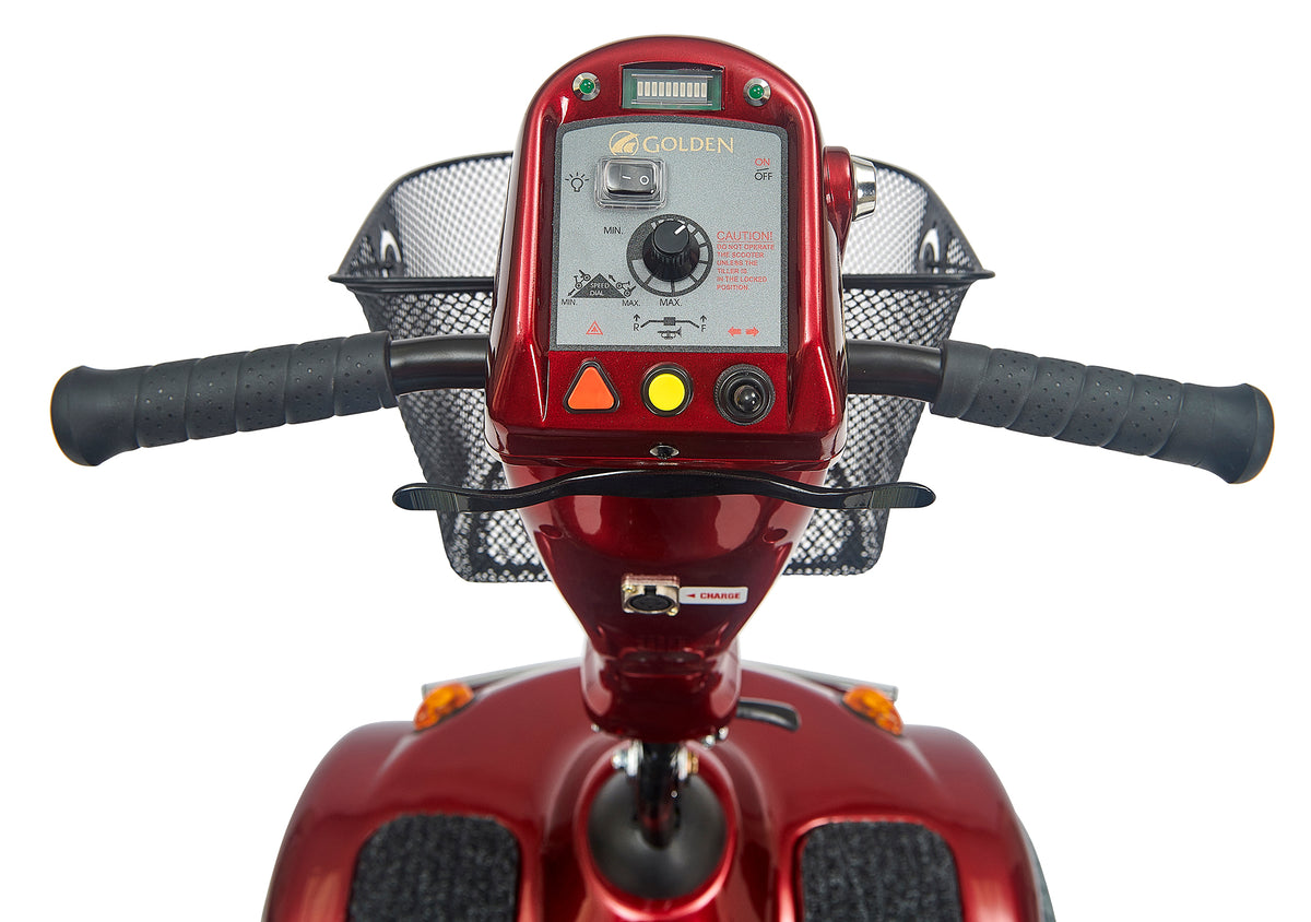 Power scooter tiller closeup showing red control panel with speed dial, battery indicator, horn button, and black wire