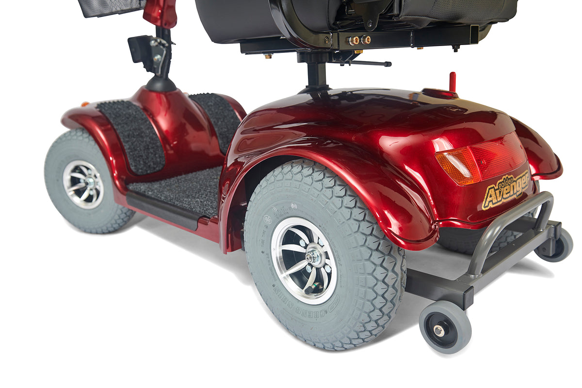 Power scooter in red with four large gray tires, rear anti-tip wheels, and black captain's seat on white background