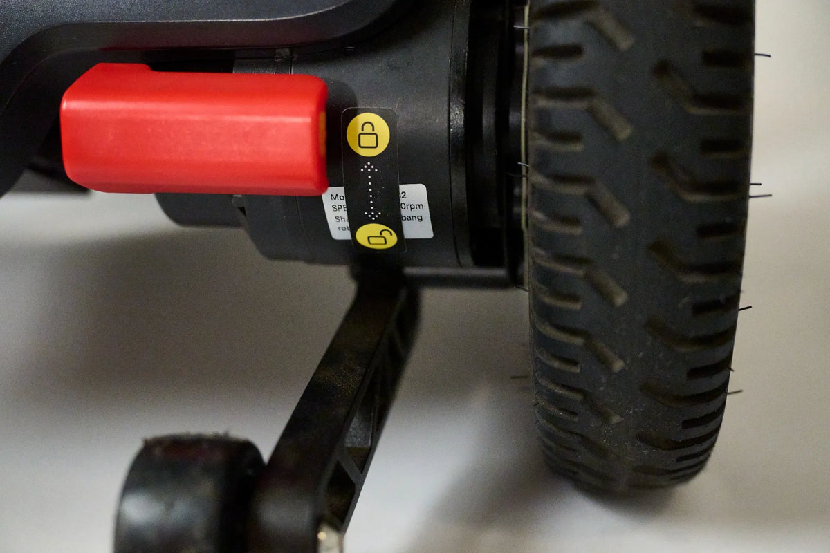 Power wheelchair rear wheel and motor assembly with red freewheel lever and yellow lock/unlock indicator stickers