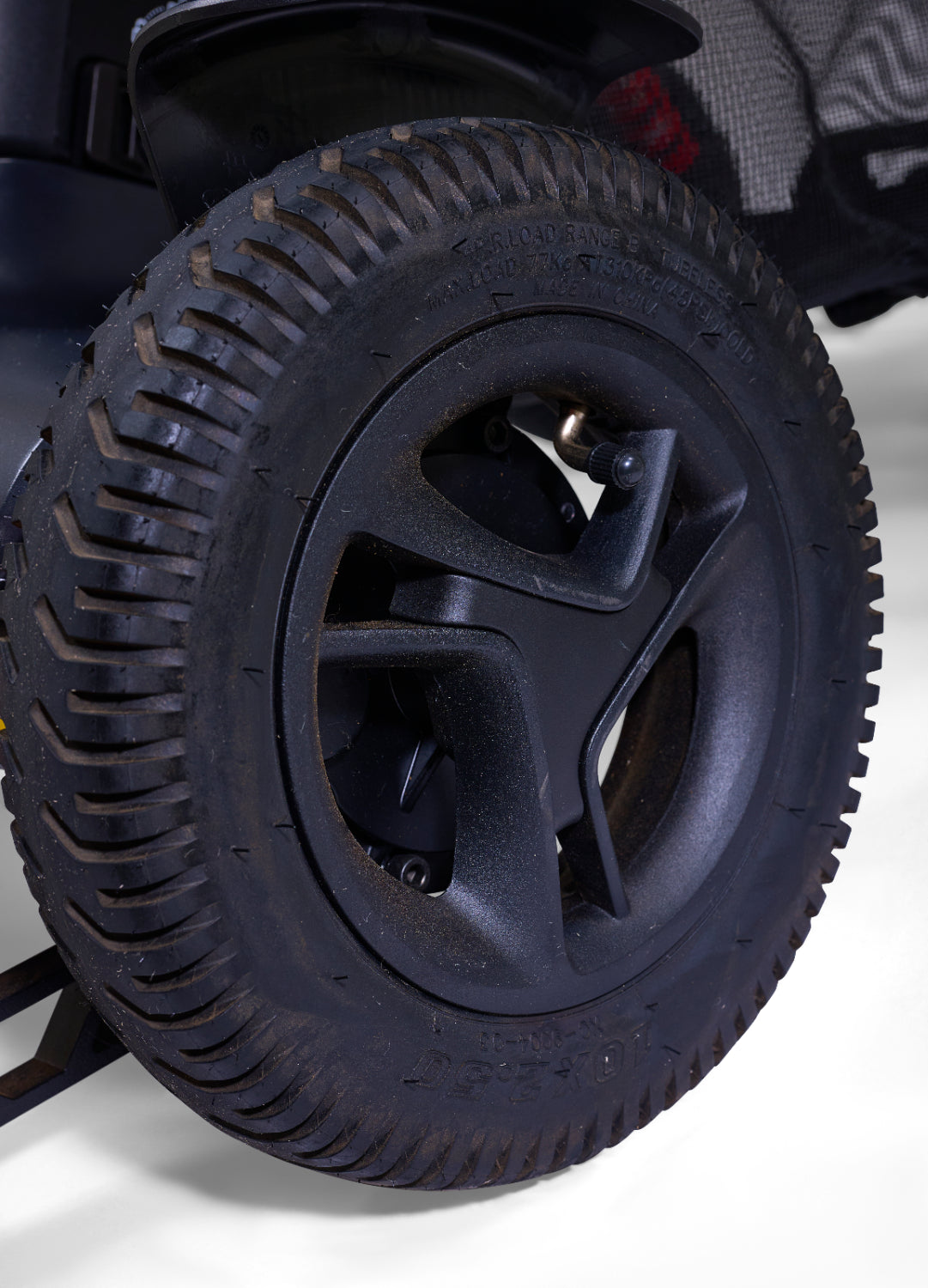 Power wheelchair rear drive wheel with black treaded tire, multi-spoke hub, and freewheel release lever