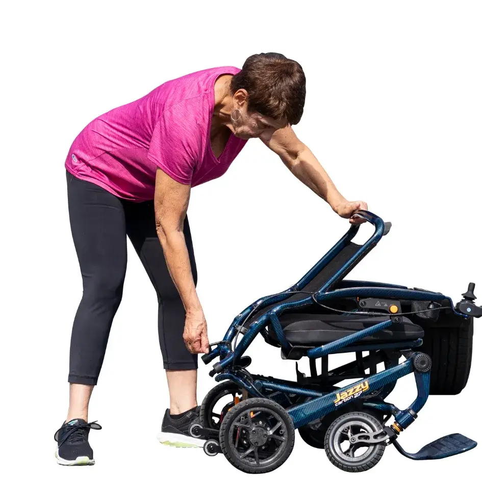Jazzy Carbon 27 power wheelchair being folded by a woman in a pink shirt, shown in partially collapsed position