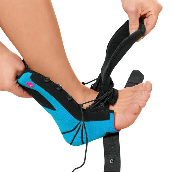 Levamed stabili-tri ankle brace in blue and black being secured on a bare foot with lace-up closure and straps
