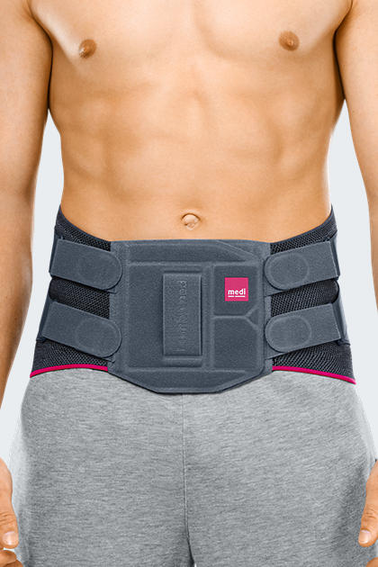 Lumbamed Facet lumbar support brace worn by male model, gray with pink trim, structured back panel and side straps visible