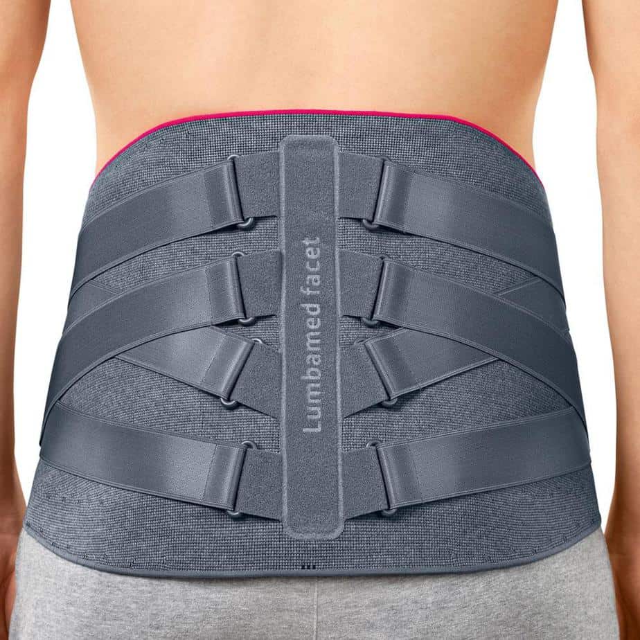 Lumbar back brace in gray with crossed tension straps, a center spinal stay, and pink trim, worn on a person's lower back