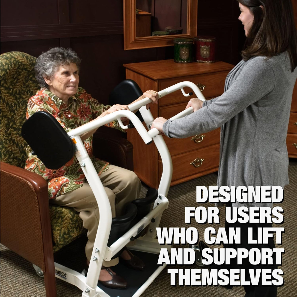Stand assist patient lift being used to help an elderly woman rise from an armchair with a caregiver's assistance indoors