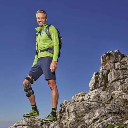 M.4s Comfort Knee Brace worn by a man hiking on rocky terrain outdoors under a clear blue sky
