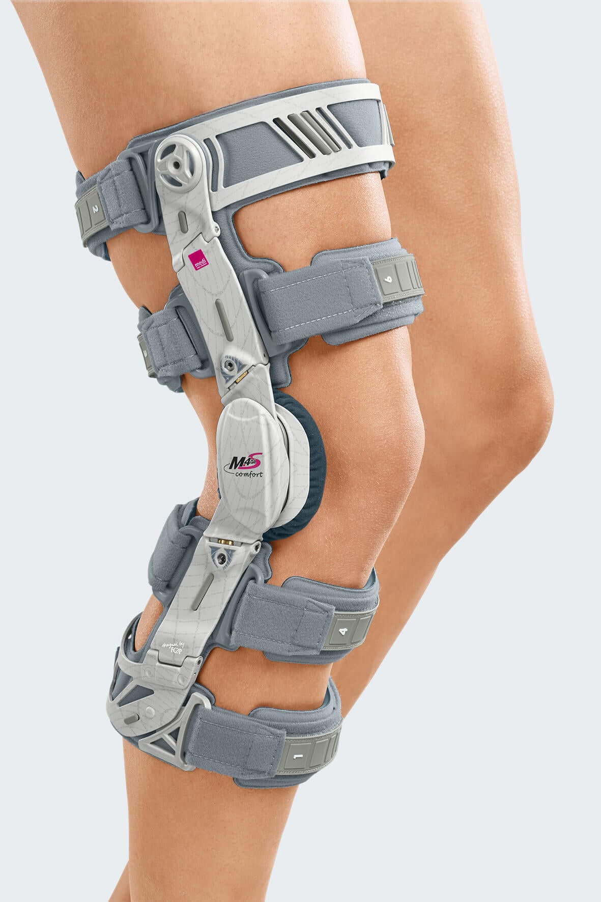 Knee brace with gray padded straps, hinged aluminum frame, and dial adjustment mechanism worn on a left leg, side view