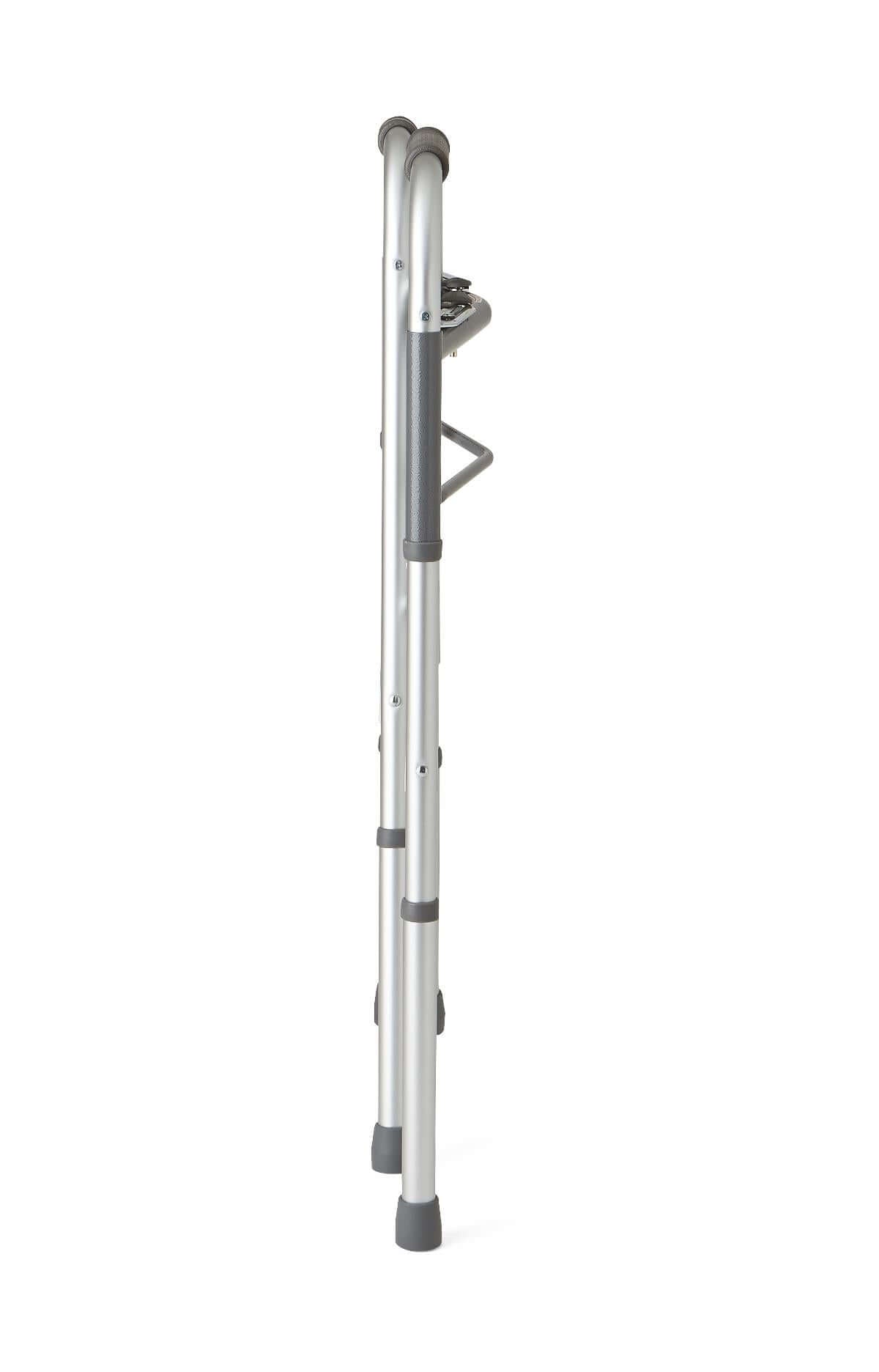 Folding walker shown collapsed from the side, silver aluminum frame with gray grip and rubber tips