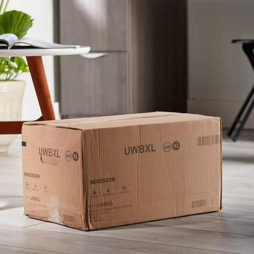 Absorbent underwear shipping box labeled UWBXL, size XL, sitting on a light wood floor near a table