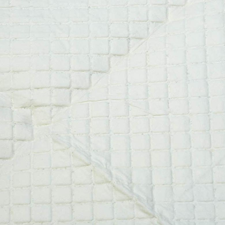 Quilted white reusable underpad with square stitching pattern, folded corner showing layered fabric construction