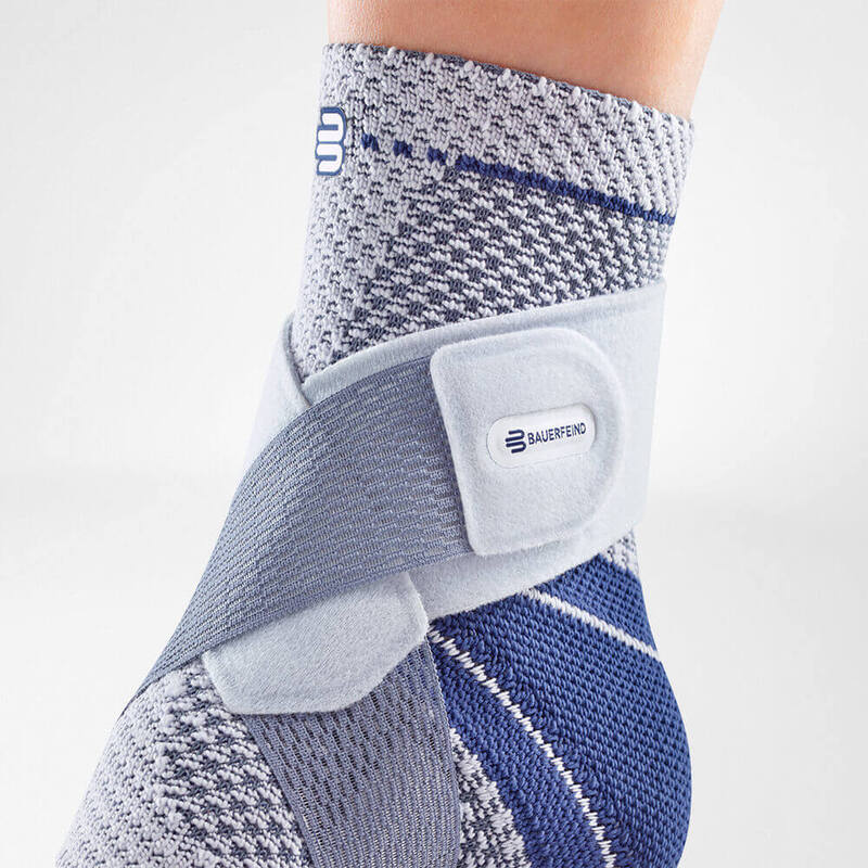 Ankle brace with gray and blue knit compression sleeve and adjustable strap with Bauerfeind logo, worn on foot