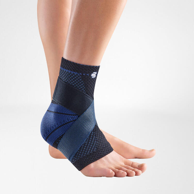 Ankle brace with navy blue knit fabric and blue figure-8 stabilizing straps worn on a bare foot and lower leg