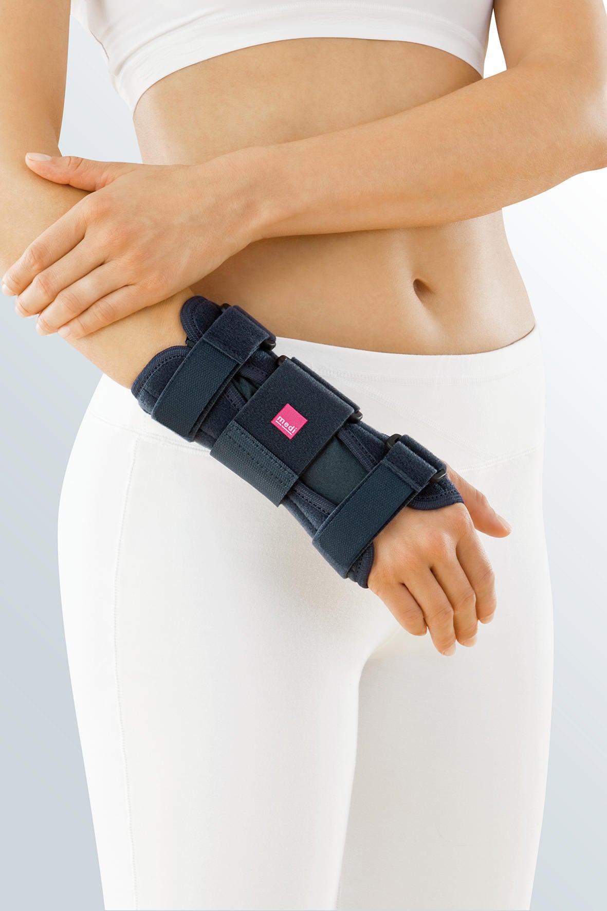 Premium wrist brace in navy blue with adjustable straps worn on a person's left wrist and forearm