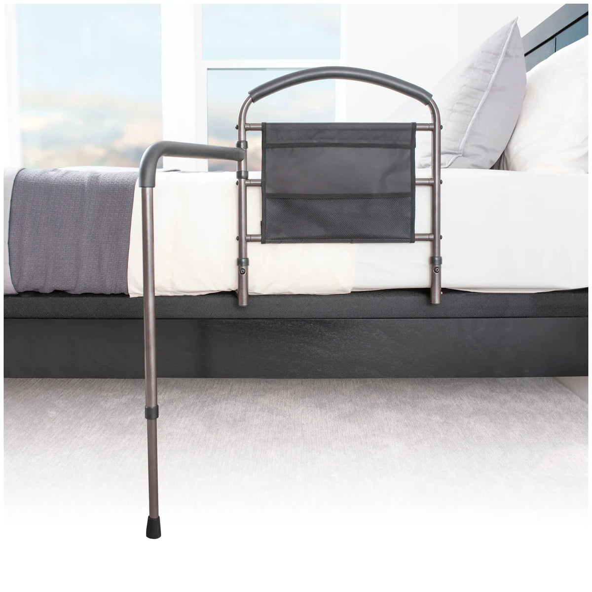 Bed rail with arched metal frame, floor support leg, and attached mesh storage pocket, shown on the side of a bed