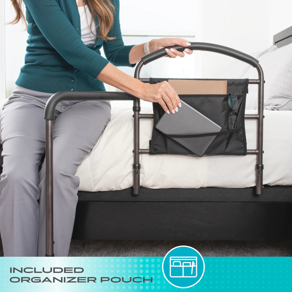 Mobility bed rail with attached black organizer pouch holding a tablet and glasses, shown beside a bed with a woman seated