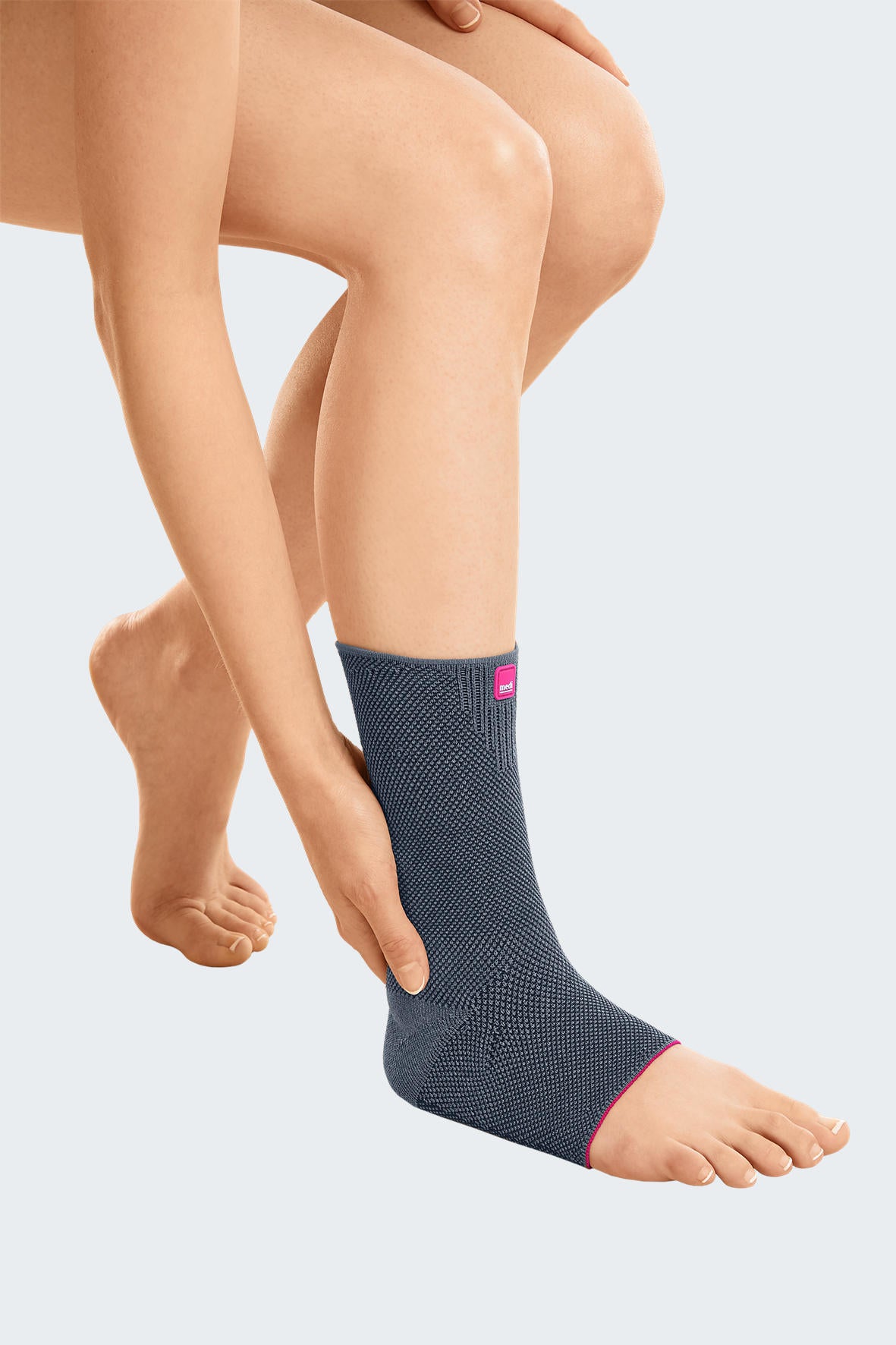 Achimed ankle support in gray knit fabric with pink trim, worn on a person's right foot and ankle