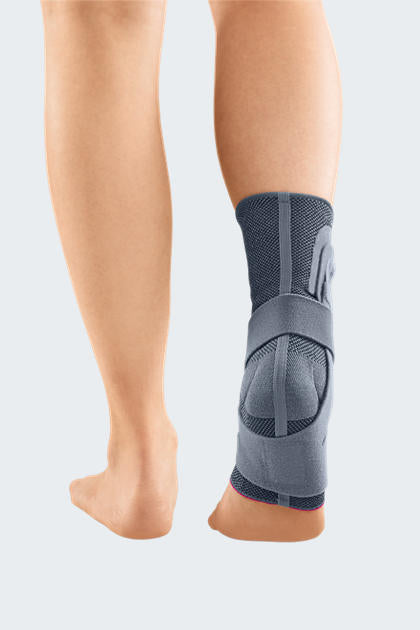 Levamed Active Ankle Support shown from behind on a person's ankle, featuring gray knit fabric with wrap straps and a padded