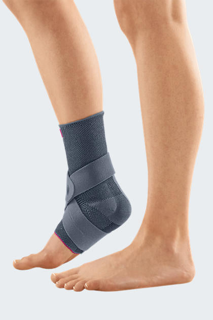 Levamed Active Ankle Support worn on left foot, gray knit brace with pink accents and figure-eight strap wrap