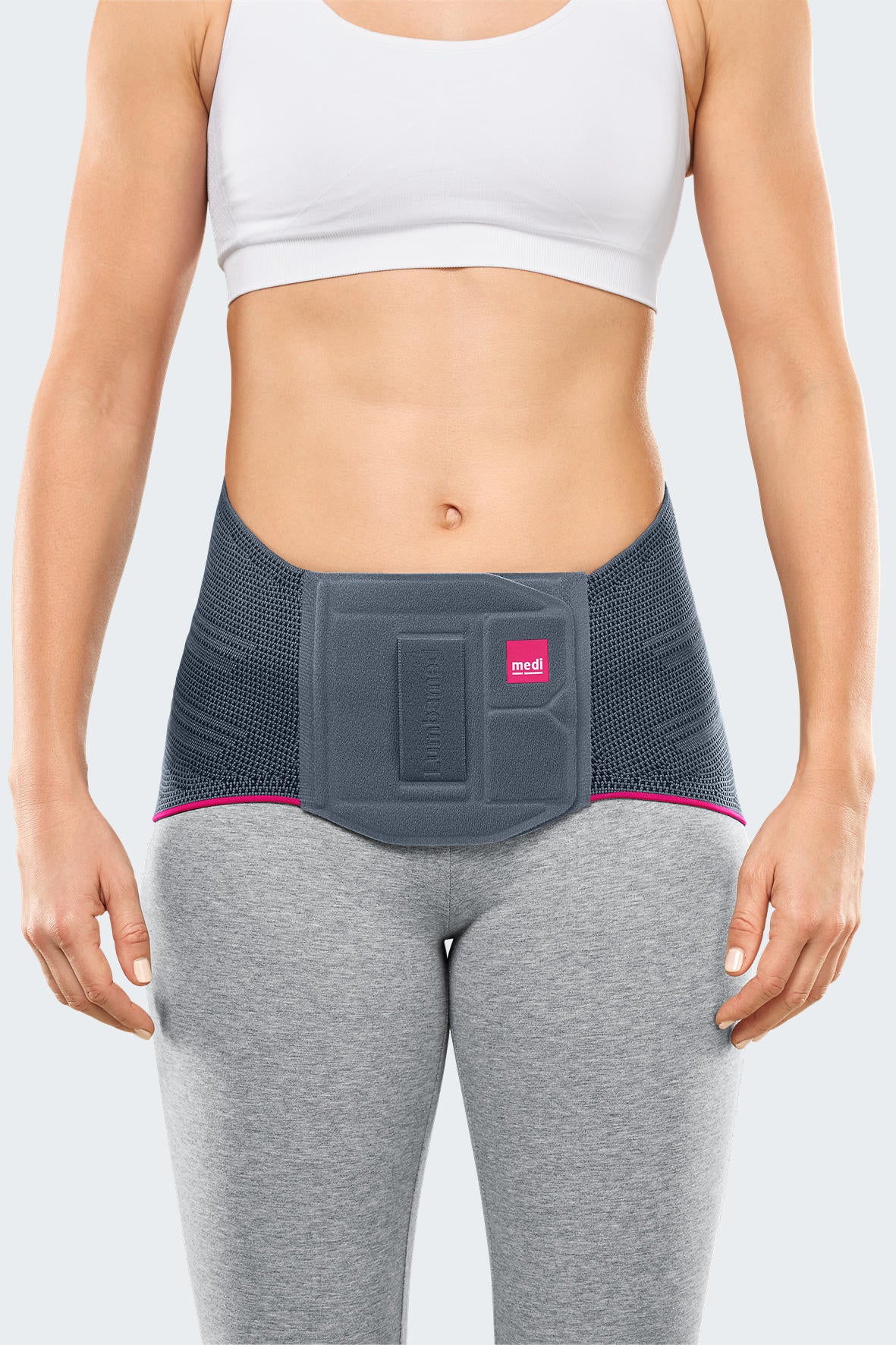 Lumbamed Basic lumbar support belt in gray with pink trim and molded front panel, worn by a woman over gray leggings