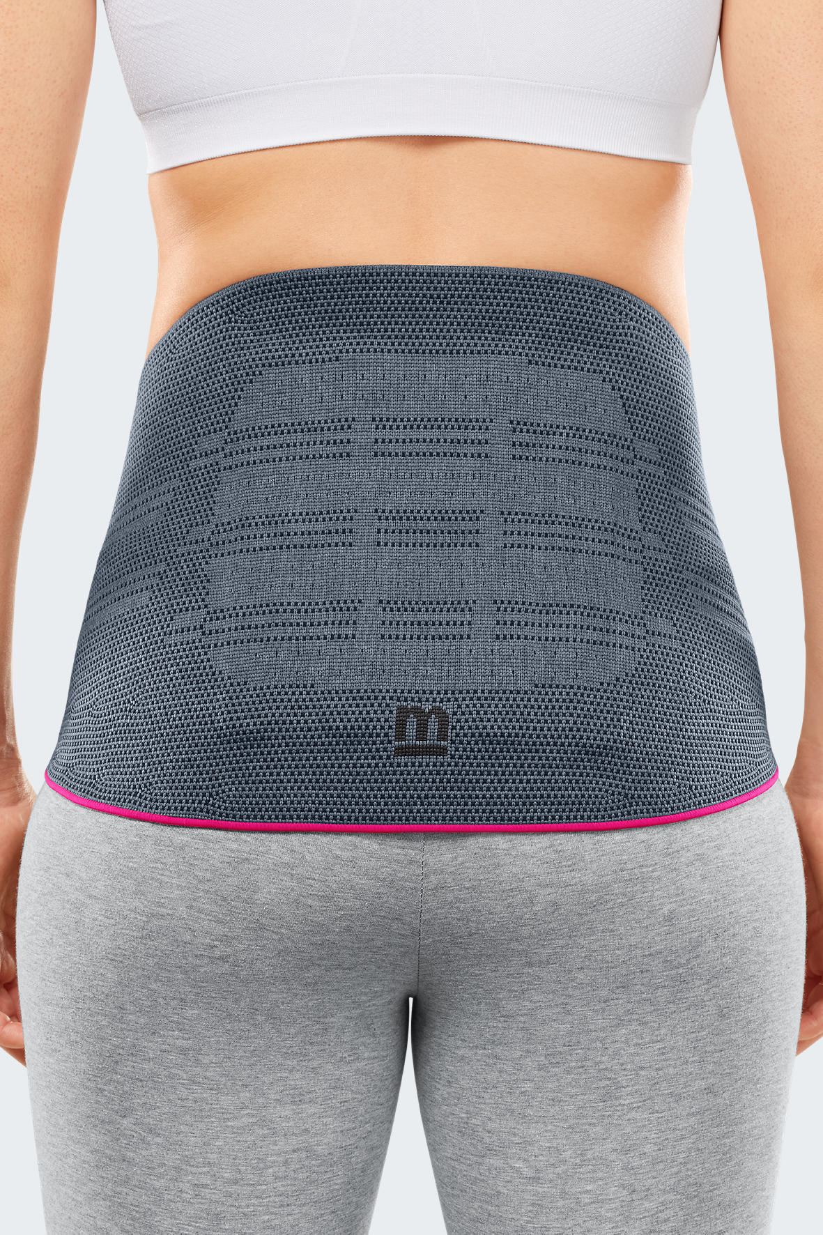 Lumbar support brace in gray knit fabric with pink trim edge, worn on a woman's lower back, back view