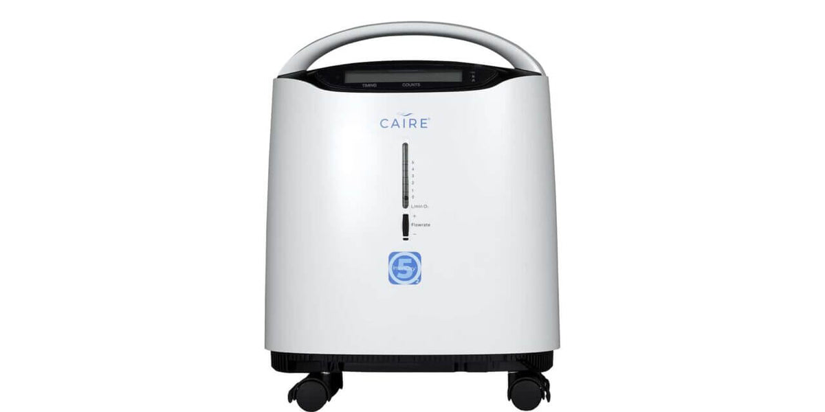Oxygen concentrator by Caire with carry handle, digital display, flow meter, blue number 5 badge, and four rolling casters