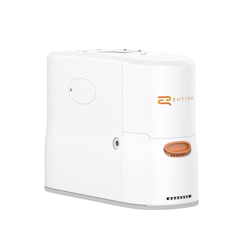 Portable oxygen concentrator in white with orange Rhythm branding and oval outlet port, shown at an angle on white background