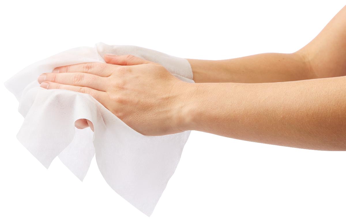 Dry cleansing wipe being used to clean hands, shown against white background