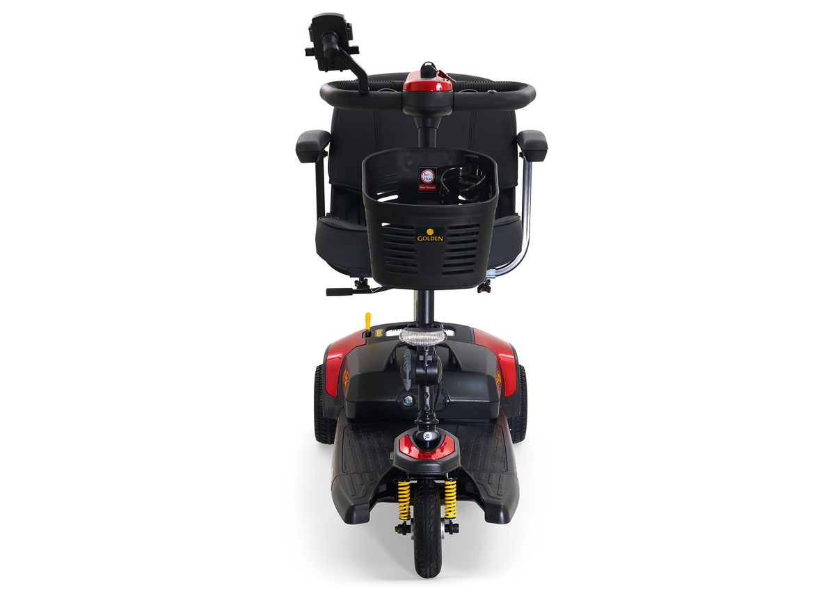 Power mobility scooter in red and black with front basket, tiller controls, padded seat, and dual front shock absorbers