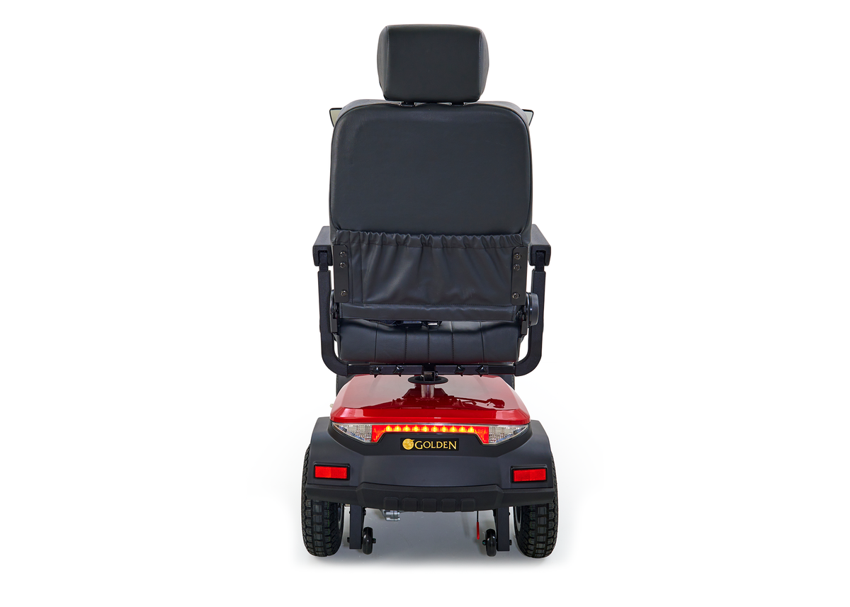 Golden mobility scooter rear view with black high-back seat, headrest, armrests, red body panel, and four wheels on white