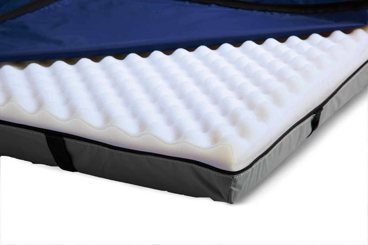 Gel foam mattress overlay with egg crate surface, partially unzipped navy cover revealing white convoluted foam layer and