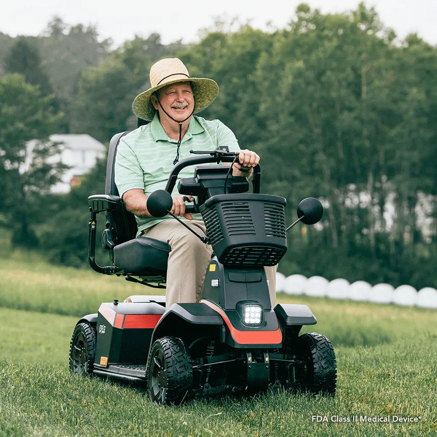 Pride PX4 heavy-duty 4-wheel mobility scooter ridden outdoors on grass by a smiling older man in a straw hat