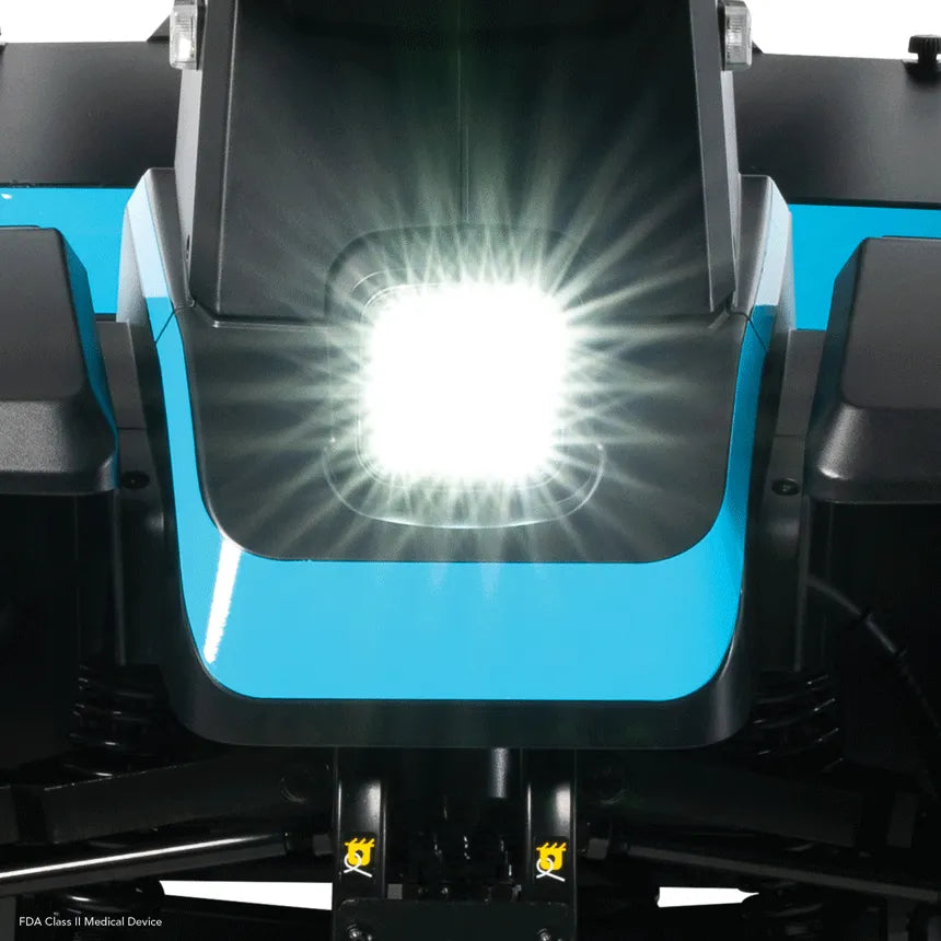 Power scooter front tiller closeup showing bright LED headlight on teal blue panel with black armrests visible on either side