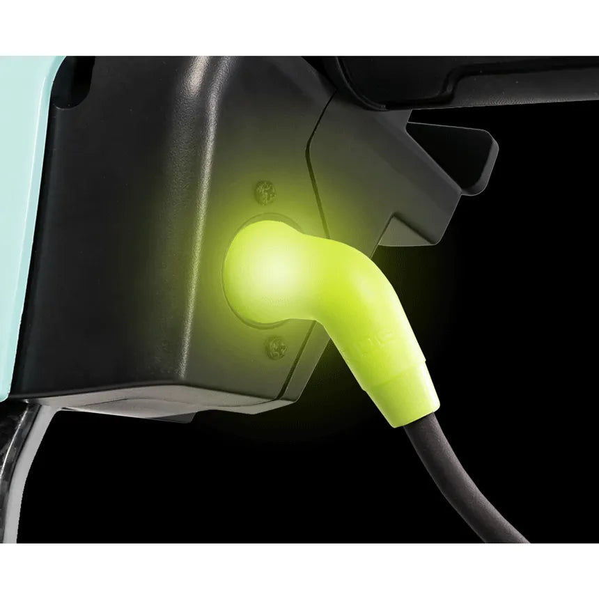 Power scooter charging port with glowing green connector plug inserted, indicating active charging status