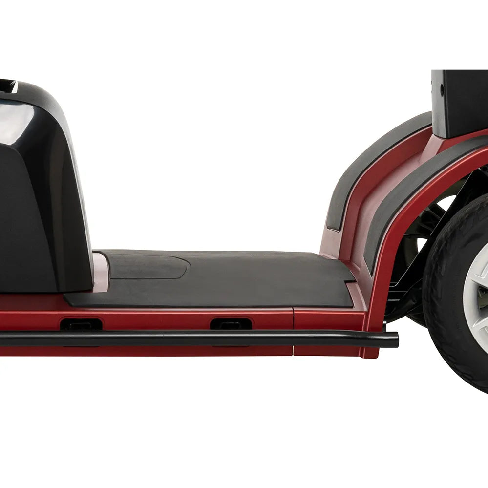 Power mobility scooter floorboard and front wheel detail showing wide black deck platform, red body panels, and gray fender