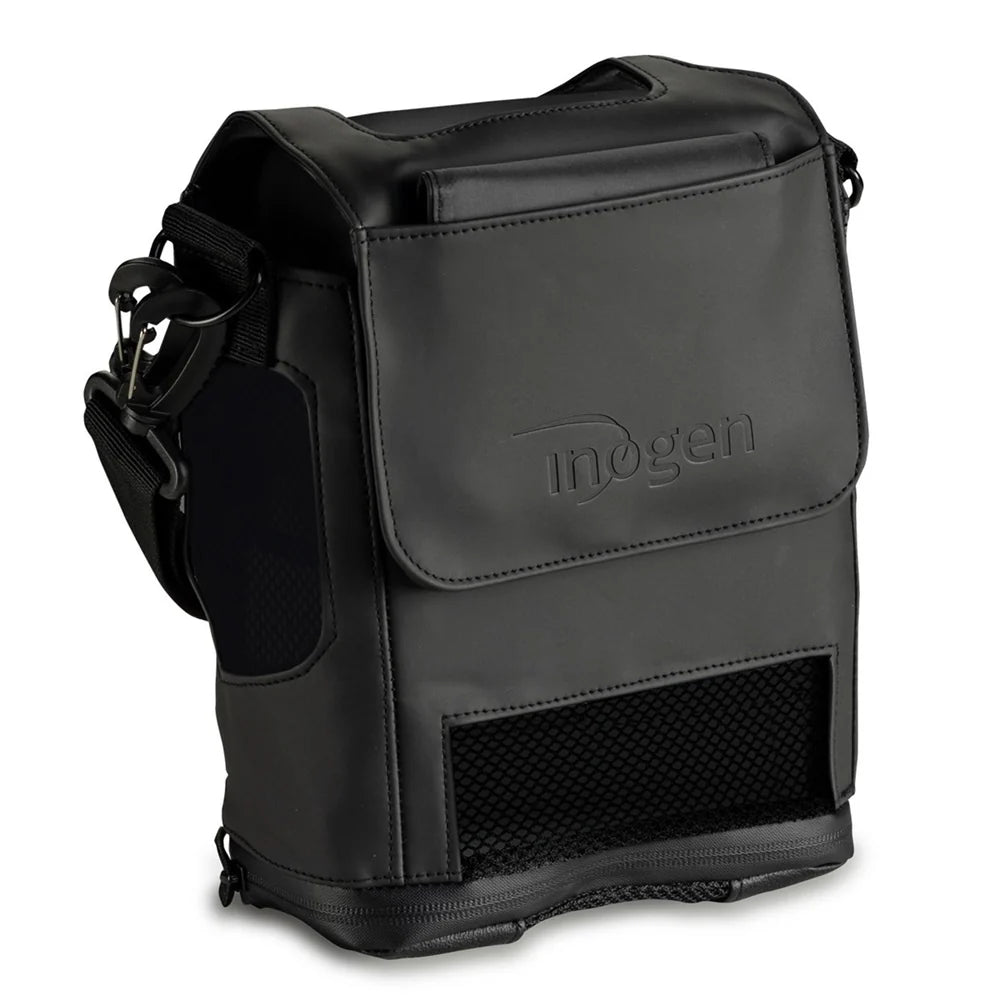 Inogen branded black carry bag with shoulder strap, flip-top closure, mesh ventilation panel, and side mesh pocket
