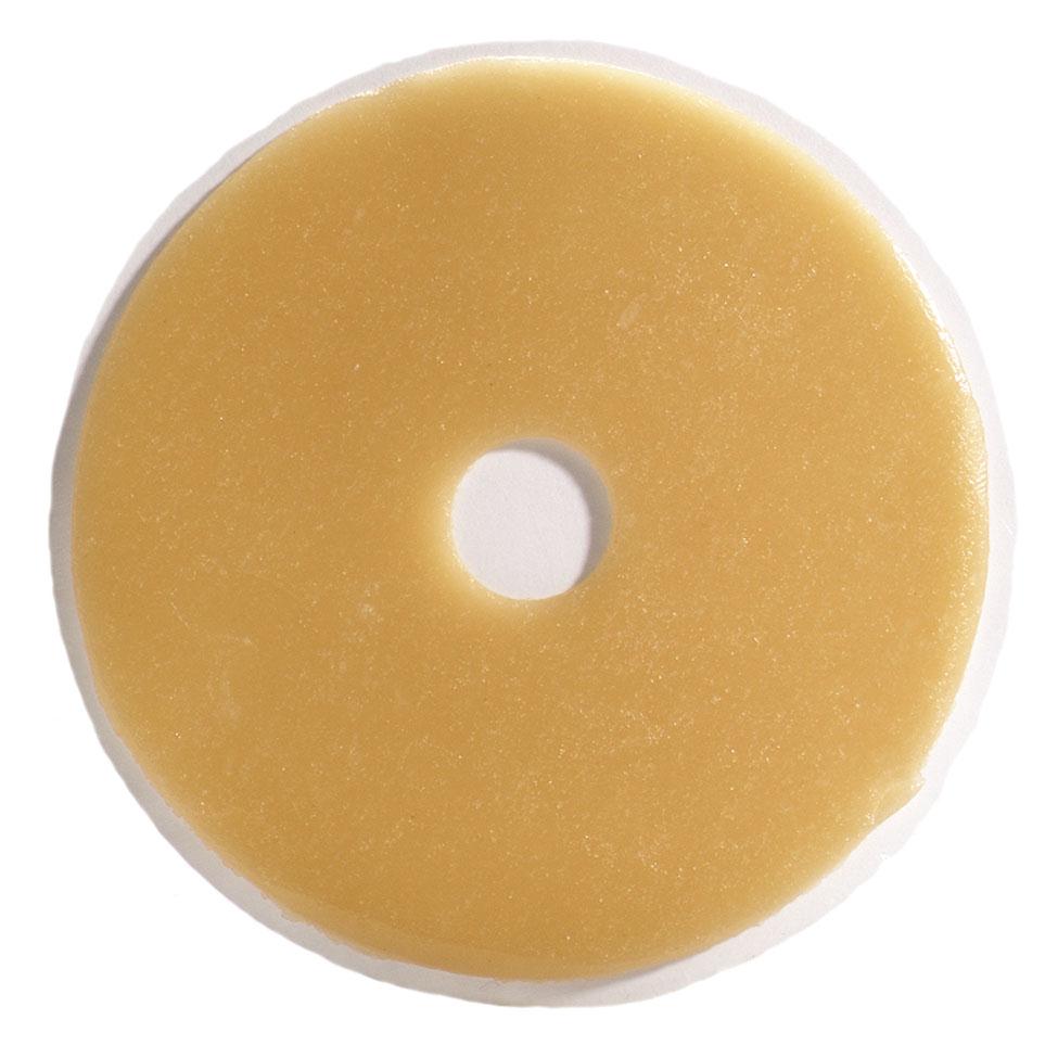 Ostomy cohesive skin barrier wafer, round beige hydrocolloid disc with small pre-cut center opening, shown on white
