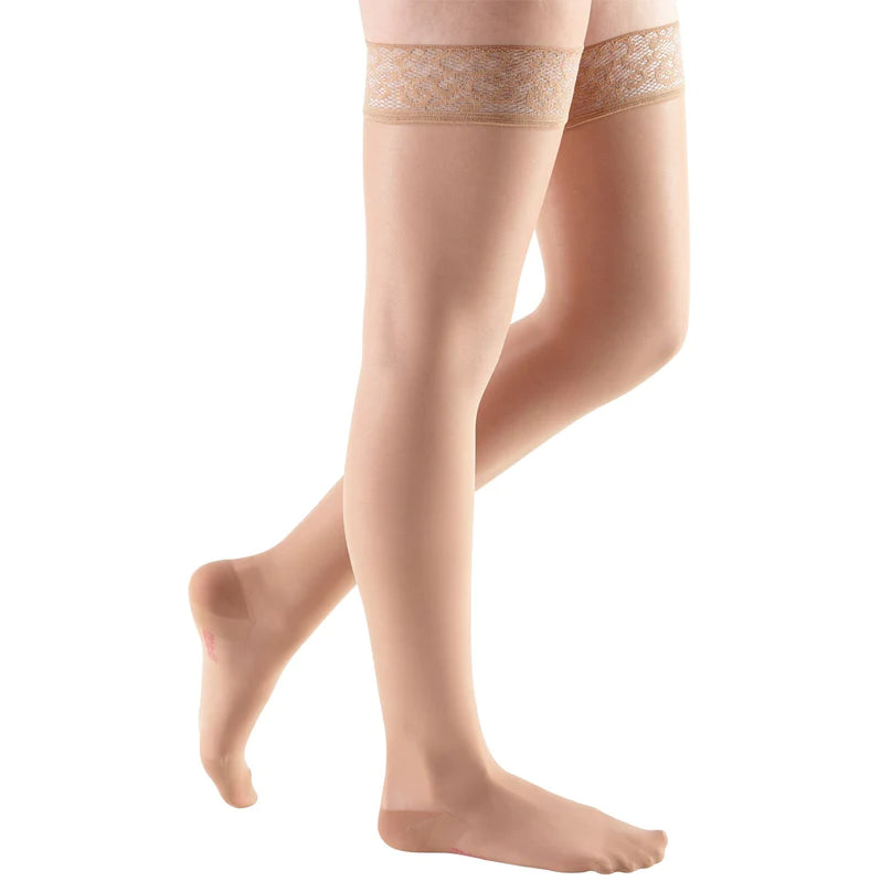 Compression thigh-high stockings in beige with sheer fabric and lace silicone top band, shown on a model's legs