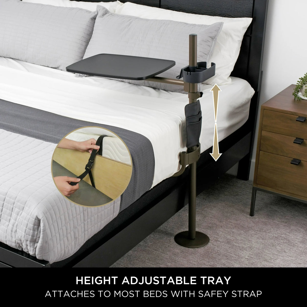 Overbed table with height-adjustable pole, swivel tray, and cup holder clamped beside a bed, with inset showing safety strap